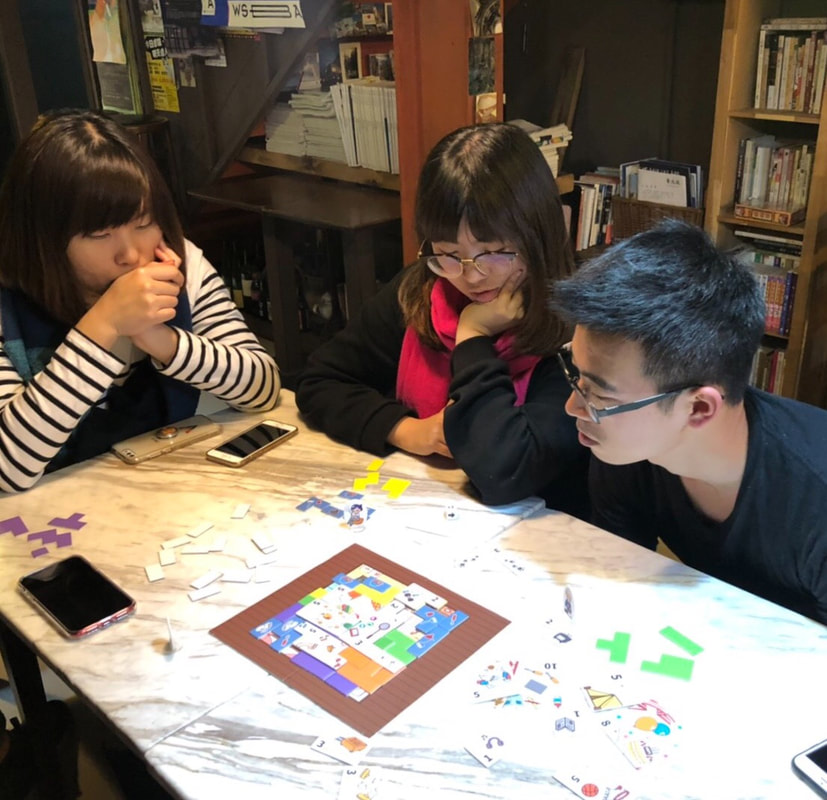 三位玩家圍著桌子體驗《家分題》,桌面上有住家圖板、板塊與家務卡